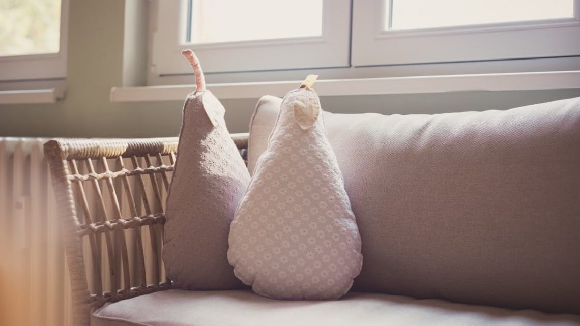 Comfortable indoor seating with pear shaped cushions on a wicker chair by a sunlit window.