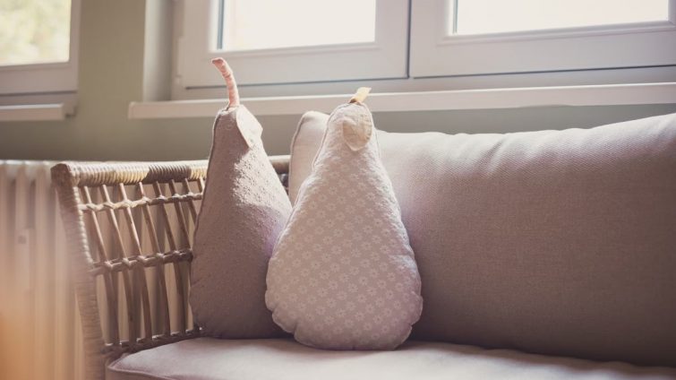 Comfortable indoor seating with pear shaped cushions on a wicker chair by a sunlit window.